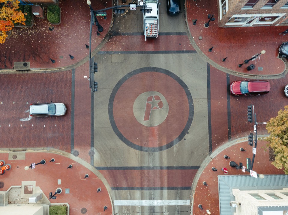 Top-down aerial of a brick plaza intersection with a star emblem, downtown Plano