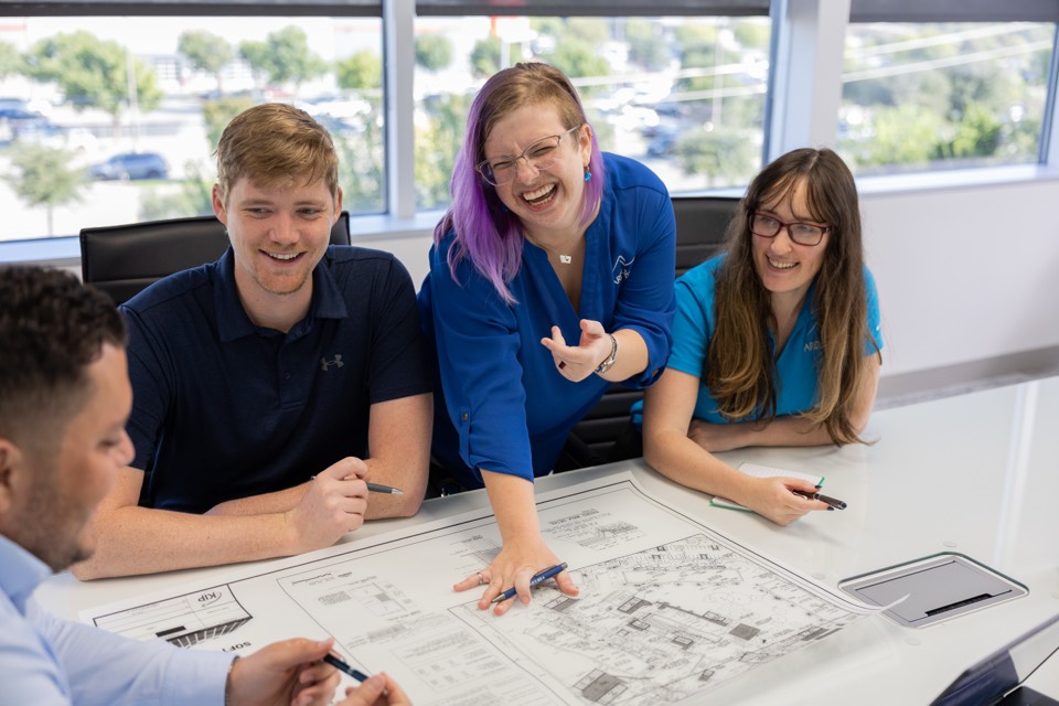 The Ardurra team laughing together over plan sheets at a conference table
